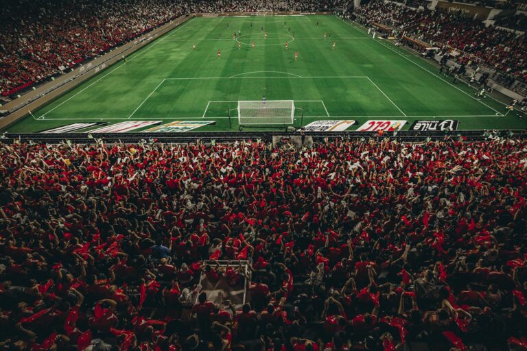 Aerial shot of a lively football match with enthusiastic fans in a packed stadium.