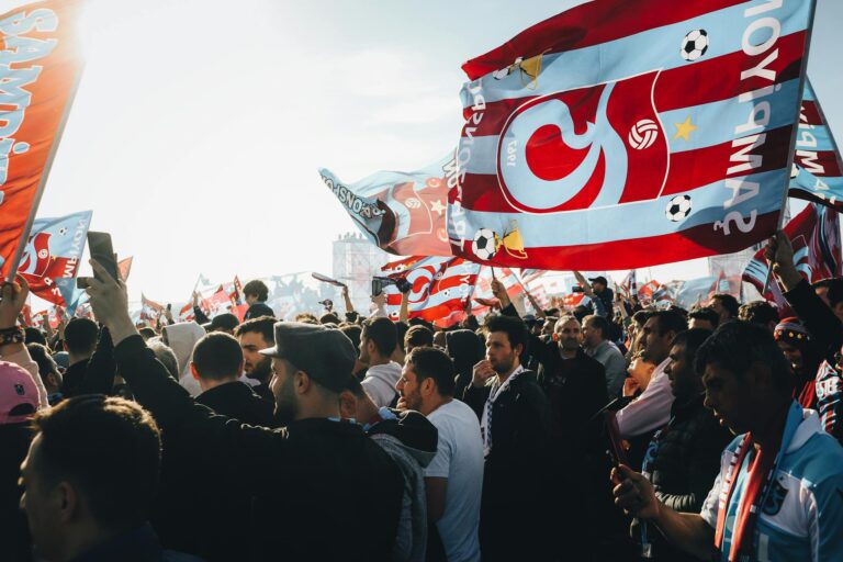 Energetic gathering with colorful flags at a lively outdoor event on a sunny day.