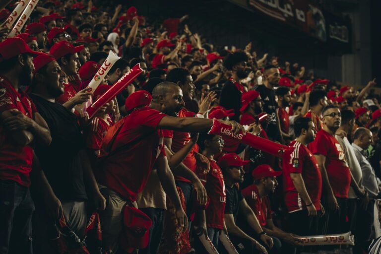 Excited football fans in red jerseys cheering passionately during a live match.